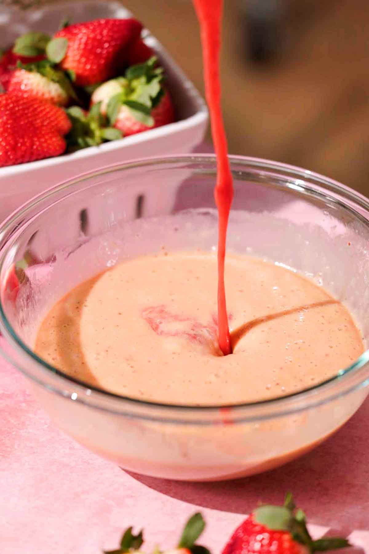 pouring strawberry sauce into bowl of whisked eggs