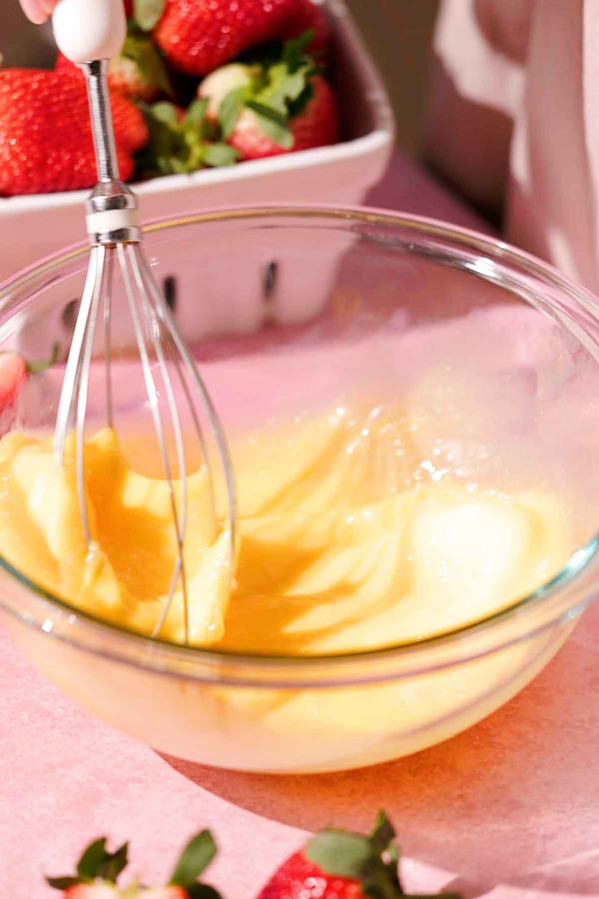 whisking eggs in glass bowl with wire whisk